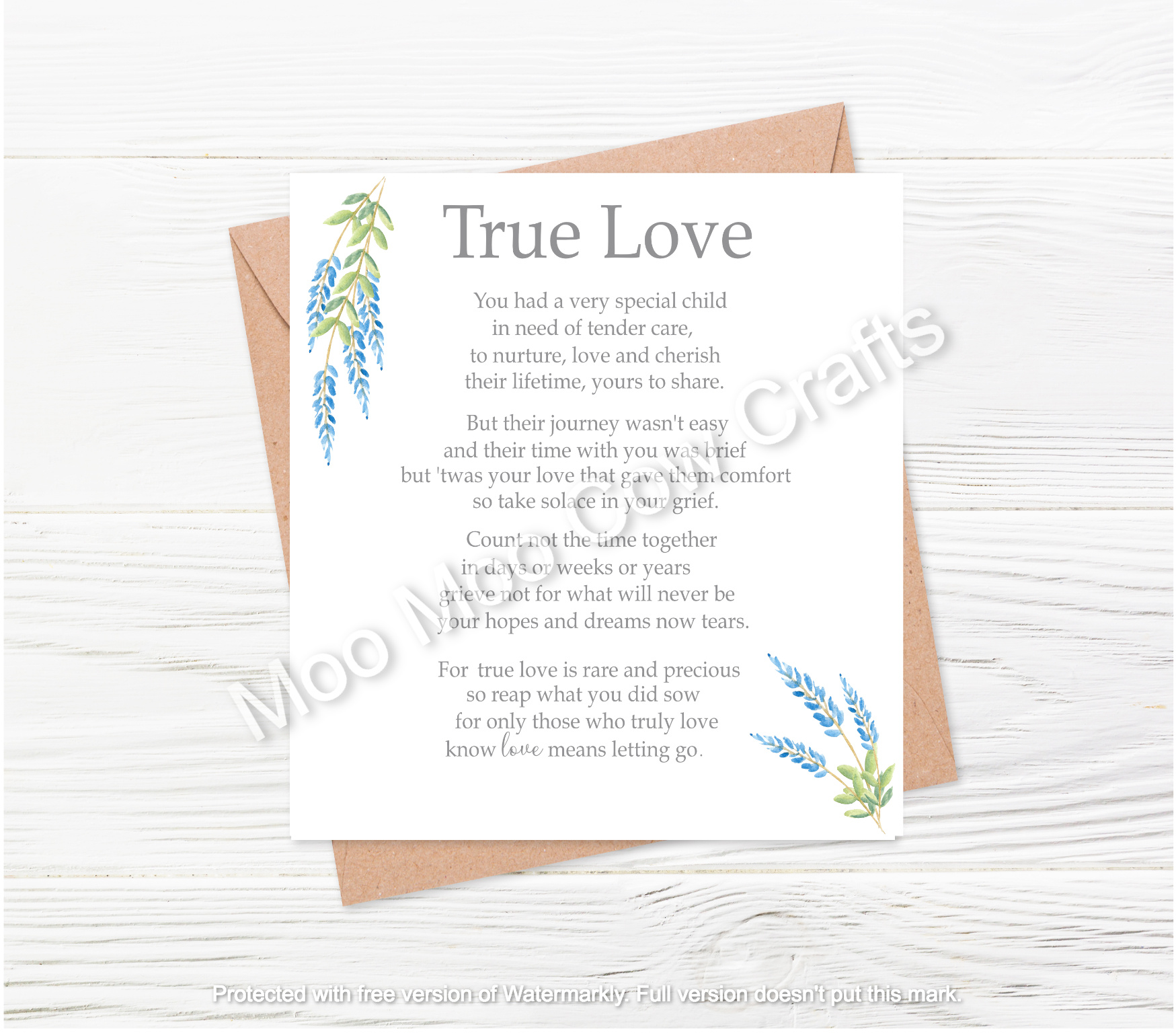 white text with blue flowers with brown envelope on white wooden background