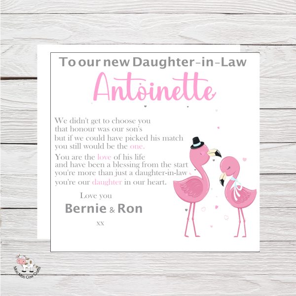 white wooden background with square white box, clipart image of two pink flamingos, it's a wedding card.
