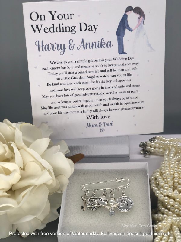 white flower, kilt pin with charms, pearls and wedding card