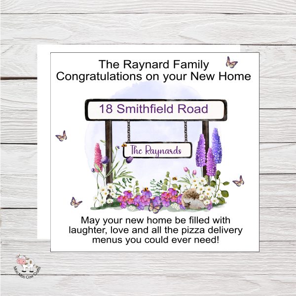 wooden background with clipart images of a street sign and flowers and black text, it's a new home card,