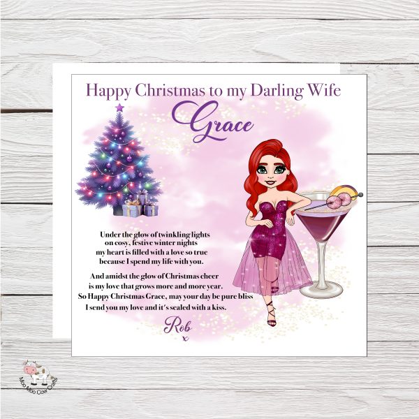 wooden background with white card with clip art image of a lady leaning on a glass, it's a christmas card.