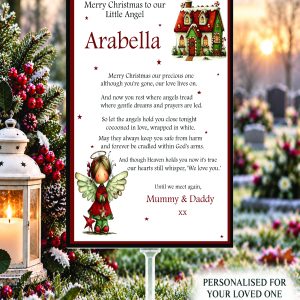 Personalised Little Angel Christmas graveside memorial card with remembrance verse, displayed on a stake beside a lantern and red winter berries.